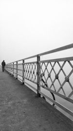 Railing by sea against clear sky