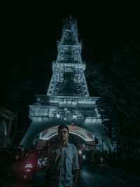 Portrait of woman standing against illuminated building at night