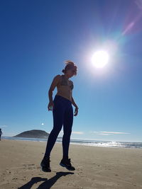 Woman jumping at shore against clear sky