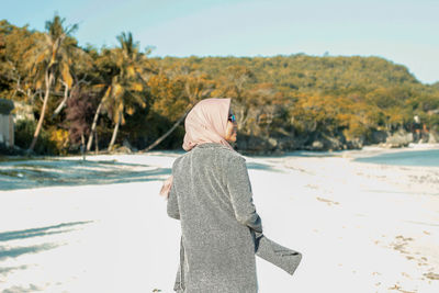 Rear view of woman on beach against sky