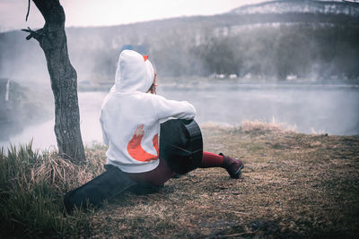 Rear view of man sitting on lakeshore