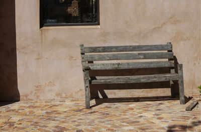 Empty bench against old building