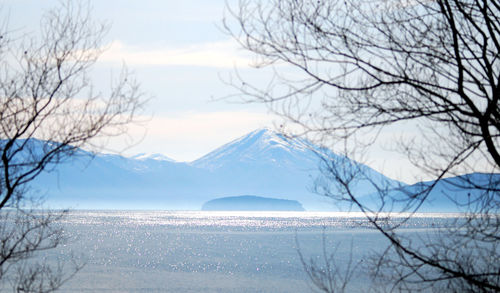 Scenic view of lake by snowcapped mountains against sky