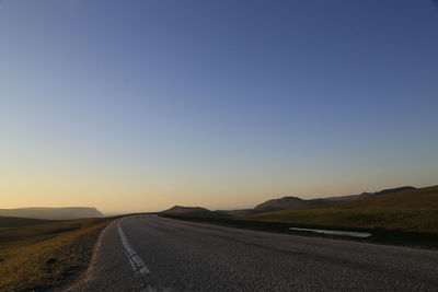 Empty road against clear sky during sunset