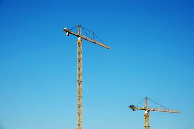 Low angle view of crane against clear blue sky