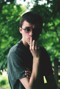 Portrait of young man wearing sunglasses against trees