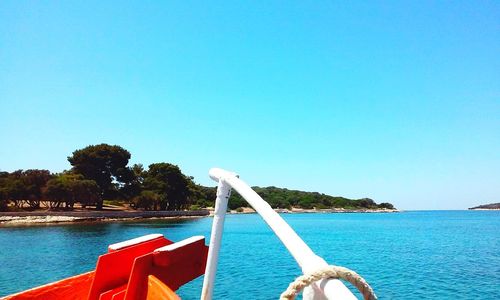 Boat sailing on sea against clear blue sky