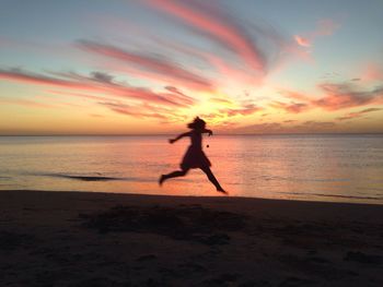 Silhouette of people on beach at sunset