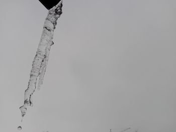 Low angle view of icicles against clear sky during winter