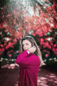 Portrait of woman standing by pink flower tree