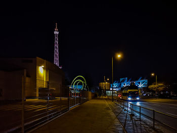 Illuminated street amidst buildings at night