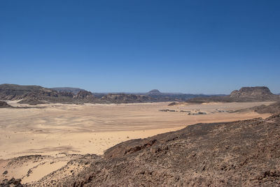 Scenic view of desert against clear blue sky