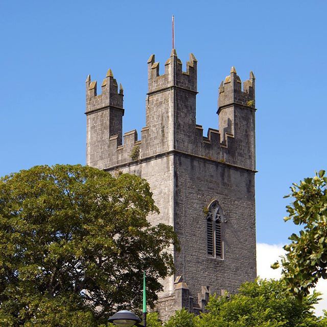 architecture, building exterior, built structure, clear sky, low angle view, tree, blue, tower, history, church, clock tower, religion, sunlight, day, tall - high, copy space, place of worship, castle, outdoors