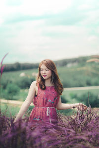 Beautiful young woman standing against sky