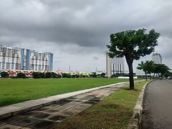 Road by buildings against sky in city