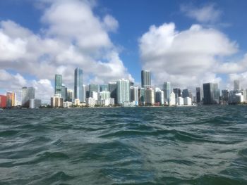 Sea by modern buildings against sky in city