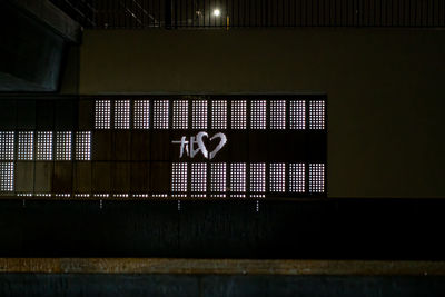 Low angle view of illuminated text on wall at night