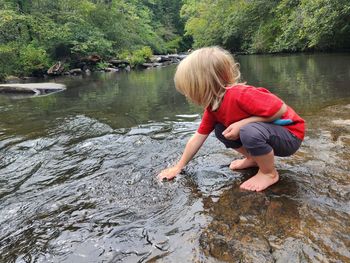 Young child kneeling to touch water
