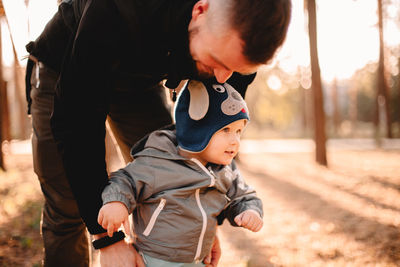 Happy father playing with son outdoors in park during sunny day