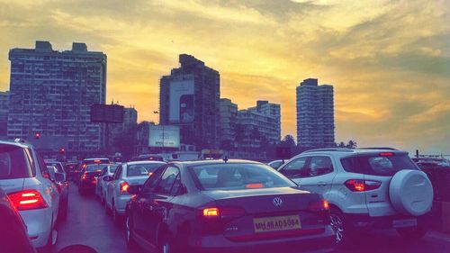 Cars on road in city against sky during sunset