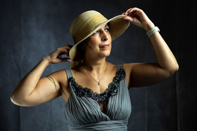 Young woman wearing hat against black background