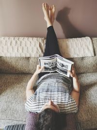 Midsection of woman reading book on sofa at home