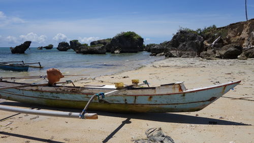 Boat moored on beach against sky