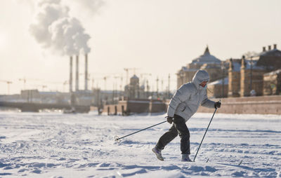 Woman skier riding on ice of the frozen neva river at sunny day, winter in st.petersburg 
