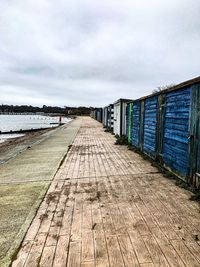 Footpath by pier in city against sky