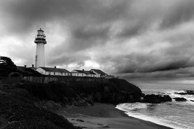 Lighthouse by sea against sky