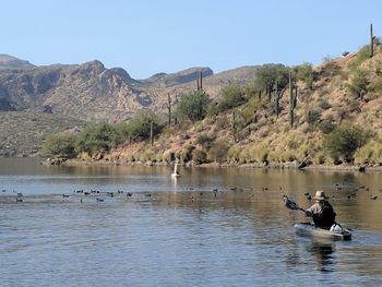 People in lake against clear sky