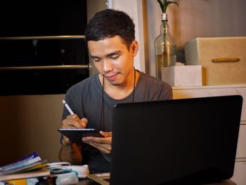 Mid adult man using mobile phone while sitting on table