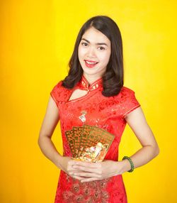 Portrait of a smiling young woman against yellow background