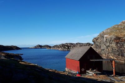 Buildings by sea against clear blue sky