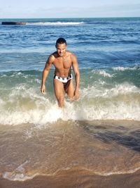 Full length of shirtless man on sea shore