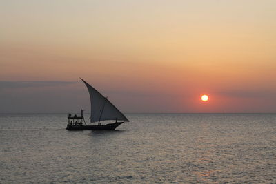 Silhouette sailboat sailing on sea against sky during sunset