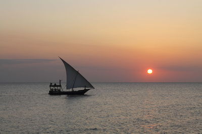 Silhouette sailboat sailing on sea against sky during sunset