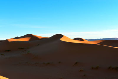 Scenic view of desert against blue sky