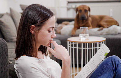 Side view of young woman drinking coffee at home