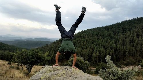 Man standing by tree on mountain against sky