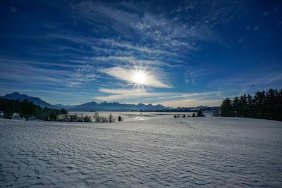 Scenic view of frozen landscape against sky during sunset