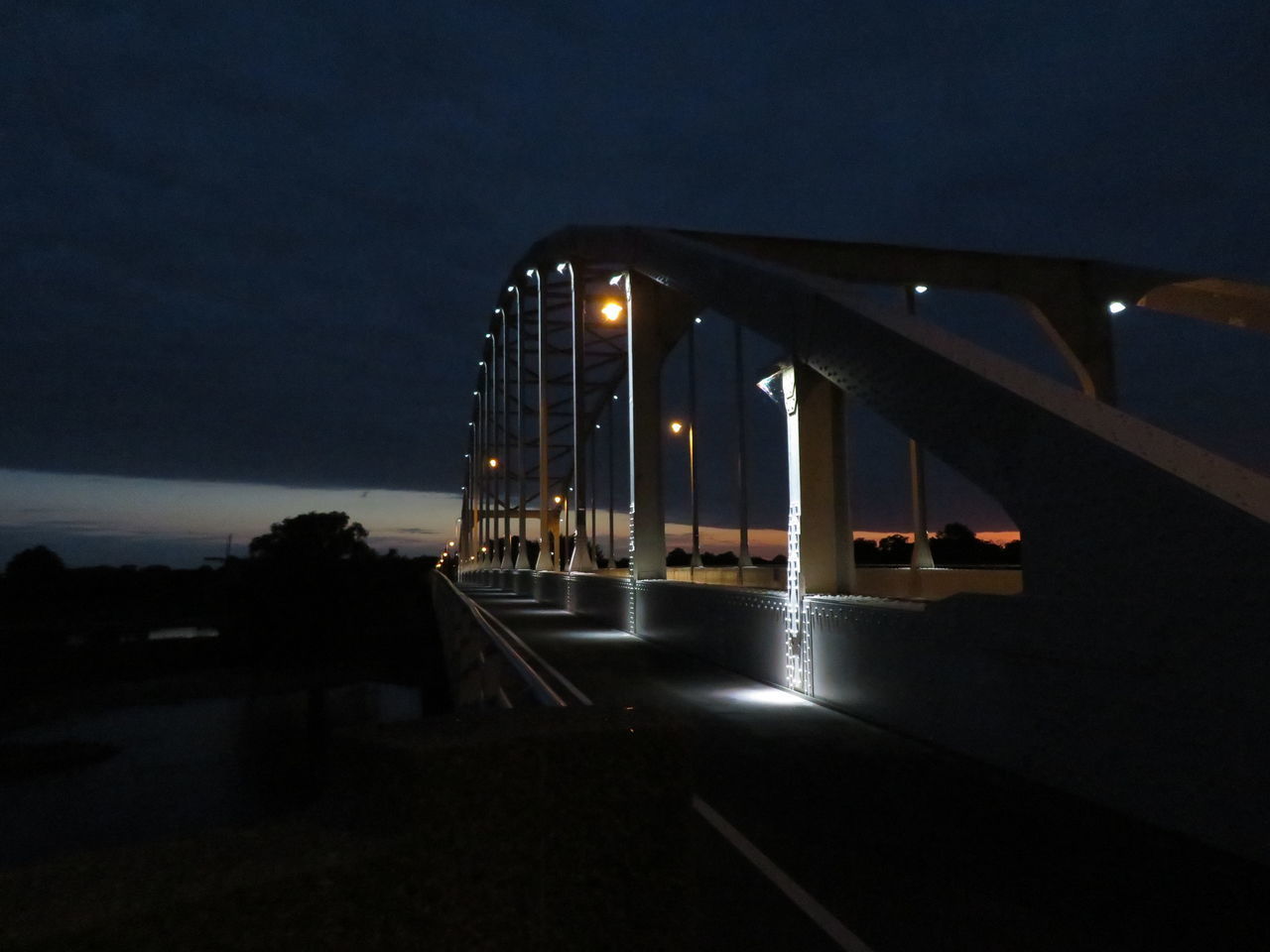 ILLUMINATED STREET BY ROAD AGAINST SKY