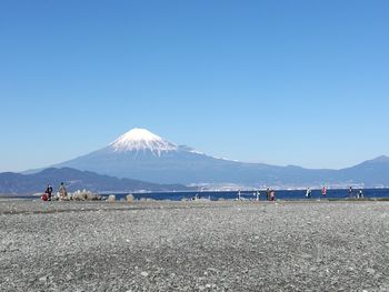 People on snowcapped mountain against blue sky