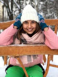 Portrait of smiling young woman sitting on bench