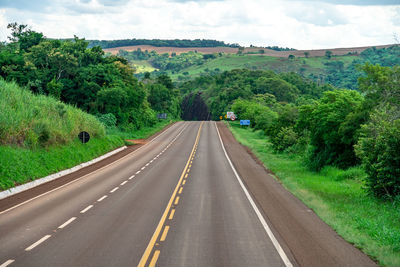 Empty road amidst trees against sky