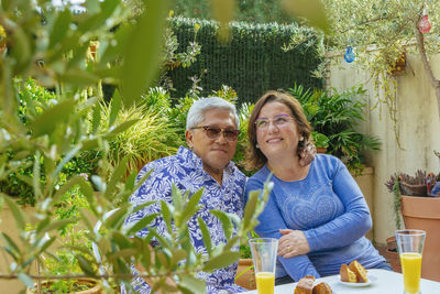 Portrait of smiling senior couple having breakfast while sitting in yard