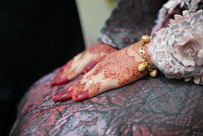 Midsection of bride with henna tattoo on hands