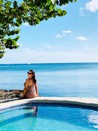 Young woman in swimming pool against sea