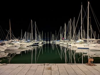 Sailboats moored in harbor at night