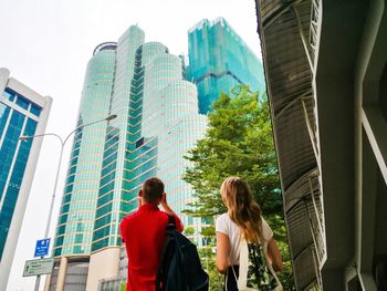 Low angle view of woman standing against modern buildings